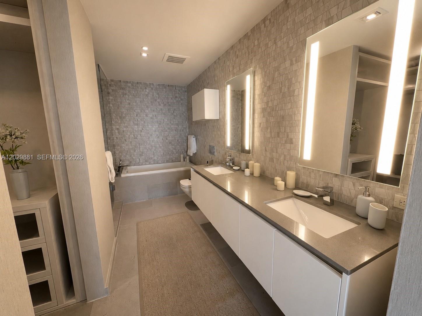 A modern bathroom features a double vanity, a soaking tub, and textured tile walls — 88 SW 7 # 3506, Miami FL 33130, MIAMI, FL