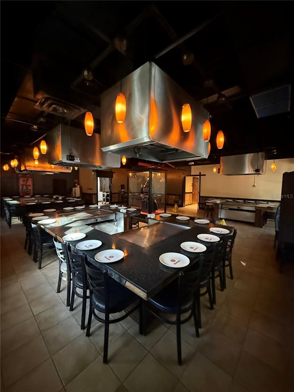 A restaurant dining room features multiple hibachi grill stations with stainless steel hoods and pendant lighting — 526 NW 60TH STREET, GAINESVILLE, FL