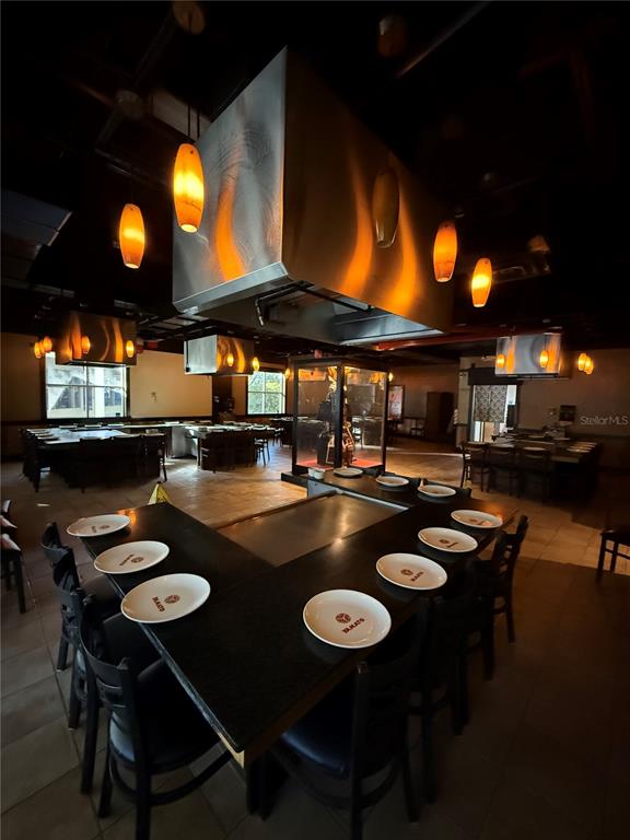 A restaurant dining room features multiple teppanyaki grill stations with black countertops and hanging lights — 526 NW 60TH STREET, GAINESVILLE, FL