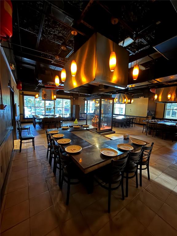 A restaurant dining room features multiple hibachi-style tables with overhead ventilation hoods and tile flooring — 526 NW 60TH STREET, GAINESVILLE, FL