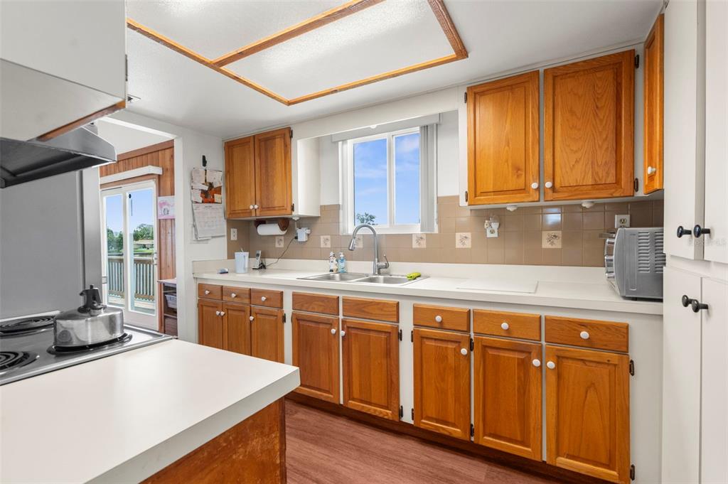 A kitchen features wood cabinets, white countertops, a double sink, and a window above — 13825 SAN JUAN AVENUE, HUDSON, FL