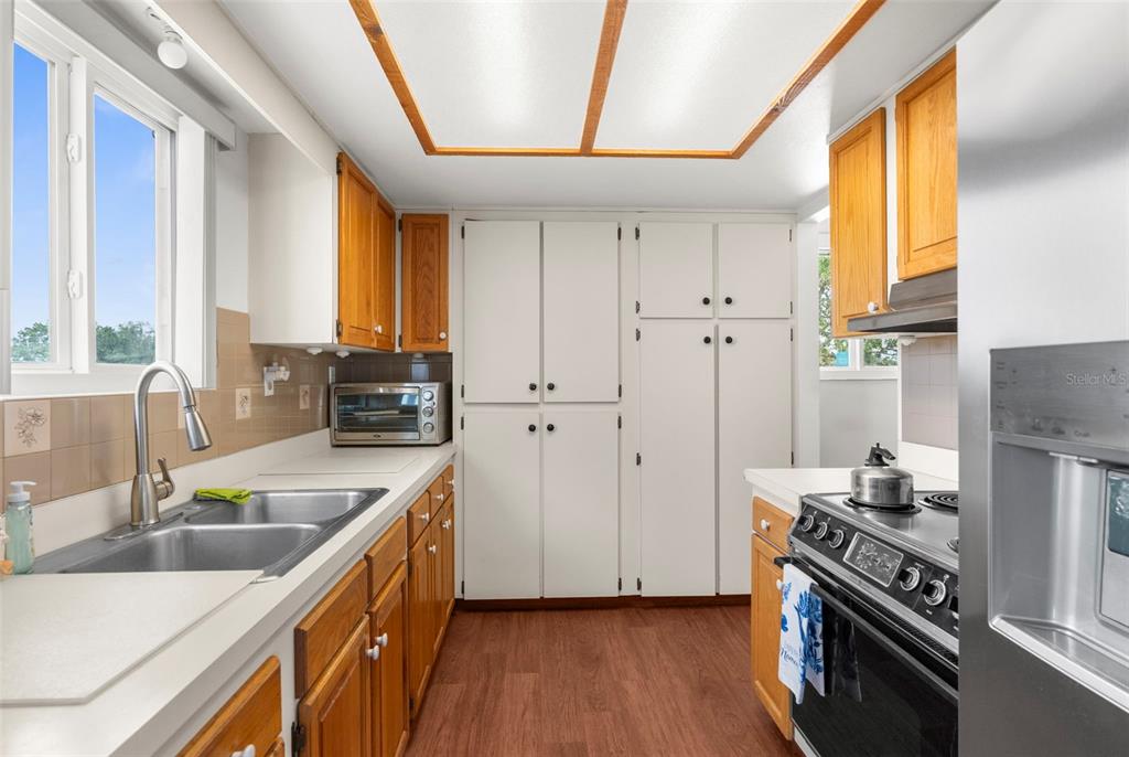 A kitchen features wood cabinets, white pantry doors, stainless steel appliances, and a double sink — 13825 SAN JUAN AVENUE, HUDSON, FL