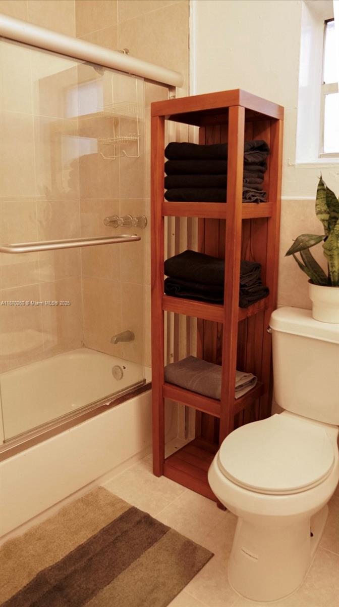 A bathroom features a glass-enclosed shower, a wooden shelving unit with towels, and a toilet — 68 NW 45th St # 2, Miami FL 33127, MIAMI, FL