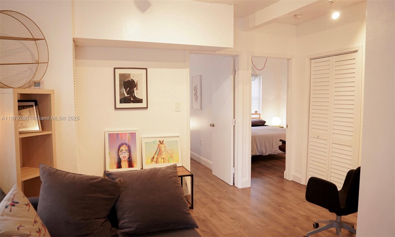 A living area with wood-look flooring leads into a bedroom through an open doorway — 68 NW 45th St # 2, Miami FL 33127, MIAMI, FL
