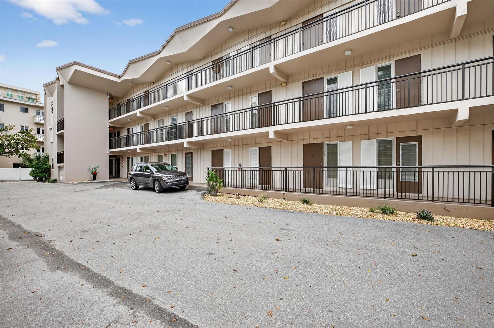 A three-story apartment building with exterior walkways and a parking area in front — 1967 S Ocean Boulevard # 103, Pompano Beach FL 33062, POMPANO BEACH, FL