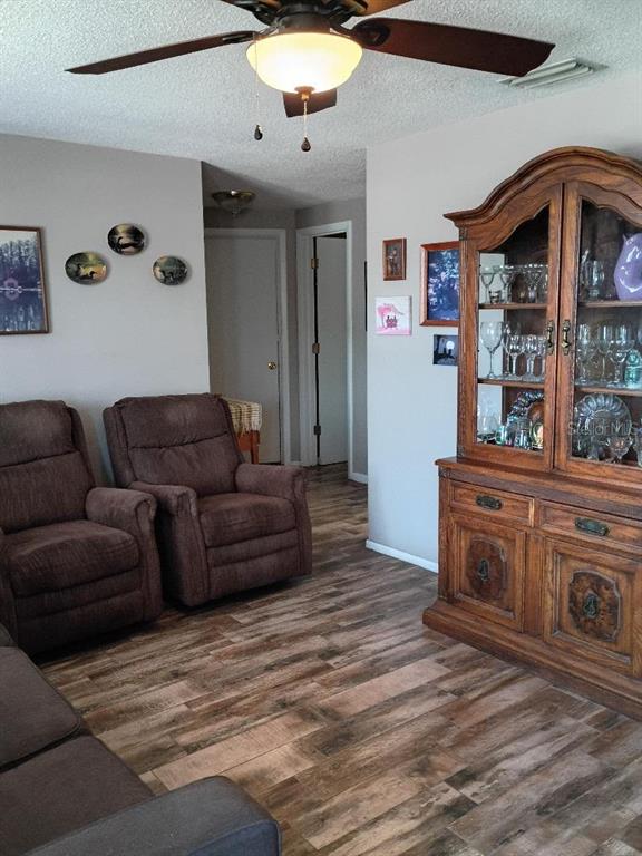 A living room features brown recliners, a wooden china cabinet, and wood-look tile flooring — 7534 ROTTINGHAM ROAD, PORT RICHEY, FL