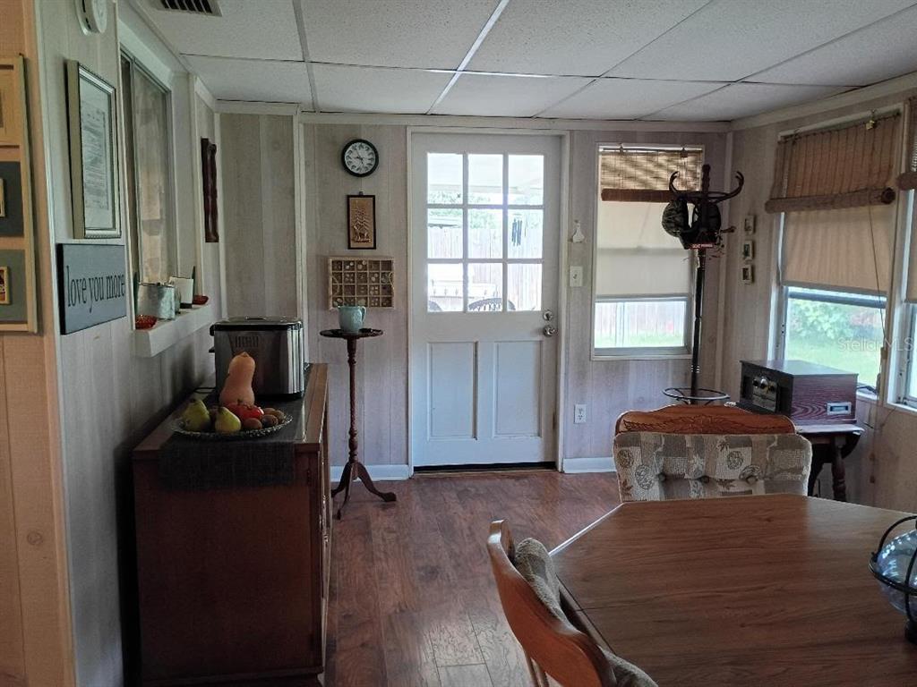 A dining area with wood-look flooring, a wooden cabinet, a table, and a glass-paneled door — 7534 ROTTINGHAM ROAD, PORT RICHEY, FL