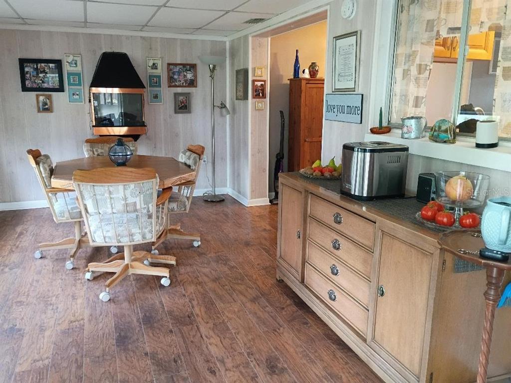 A dining area features wood-look flooring, a fireplace, a wooden sideboard, and a table with chairs — 7534 ROTTINGHAM ROAD, PORT RICHEY, FL
