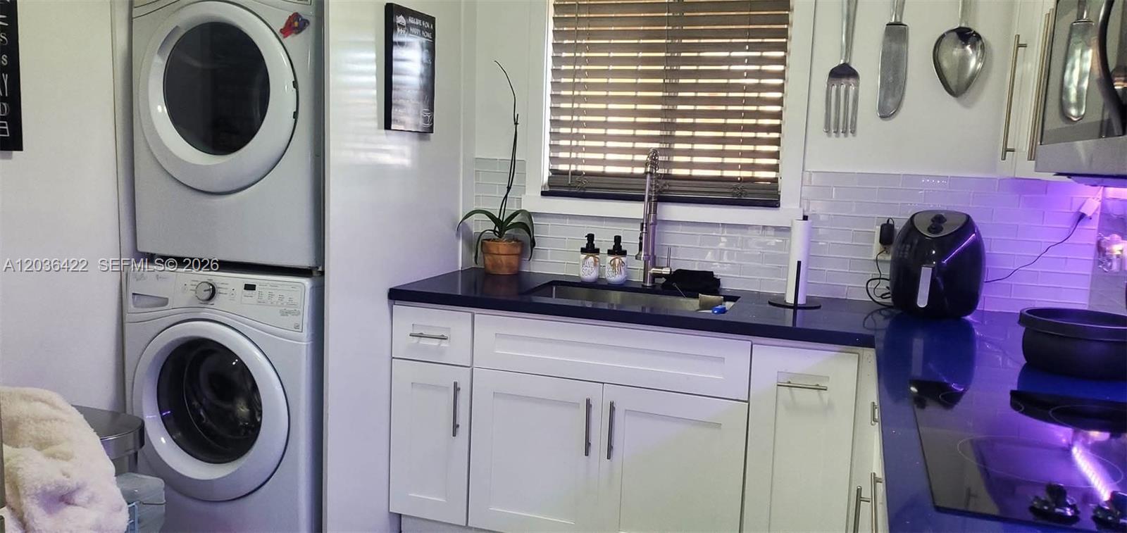 A kitchen features white cabinets, a dark countertop, a sink, and a stacked laundry unit — 7835 W 30th Ct # 104, Hialeah FL 33018, HIALEAH, FL