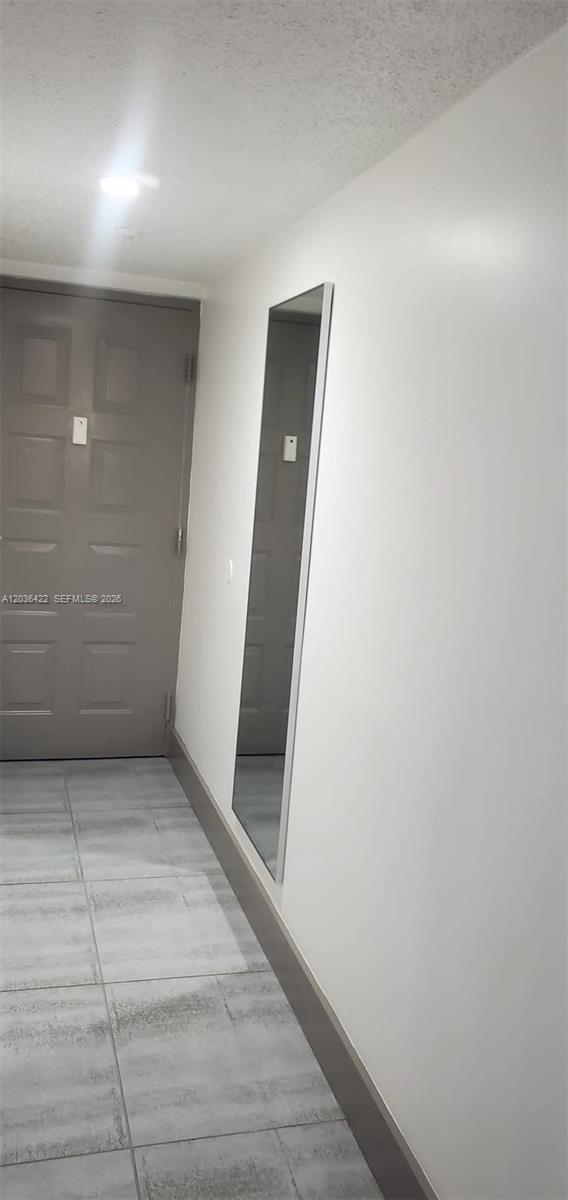 A hallway features light gray tile flooring, a gray door, and a tall wall mirror — 7835 W 30th Ct # 104, Hialeah FL 33018, HIALEAH, FL