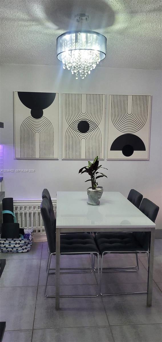 A dining room features a white table, four black chairs, and three abstract wall art pieces — 7835 W 30th Ct # 104, Hialeah FL 33018, HIALEAH, FL