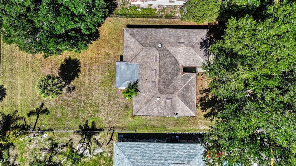 An aerial view shows a house with a shingled roof surrounded by trees and grass — 851 ROLLING WOODS LANE, LAKELAND, FL