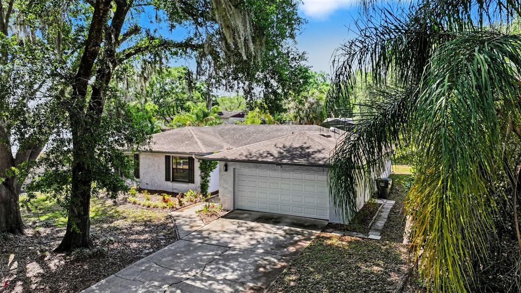 A single-story house with a white exterior, a two-car garage, and a concrete driveway — 851 ROLLING WOODS LANE, LAKELAND, FL