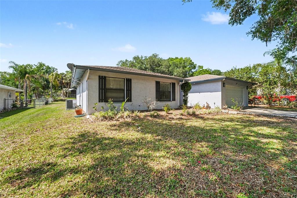 A single-story house with a detached garage and a grassy yard under a blue sky — 851 ROLLING WOODS LANE, LAKELAND, FL