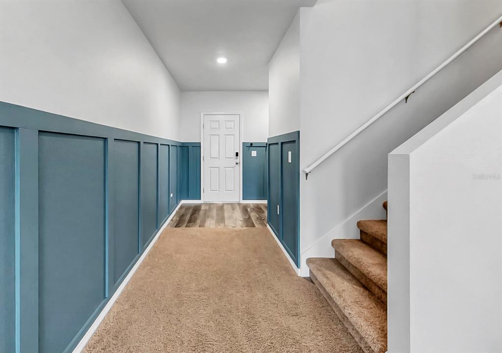 An entryway features blue board and batten walls, carpeted flooring, and a staircase — 13108 SHUMARD WAY, RIVERVIEW, FL