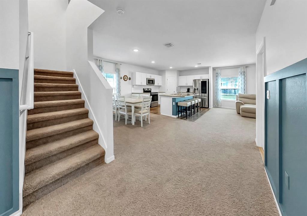 An open-concept living area features carpeted stairs, a dining space, and a modern kitchen — 13108 SHUMARD WAY, RIVERVIEW, FL