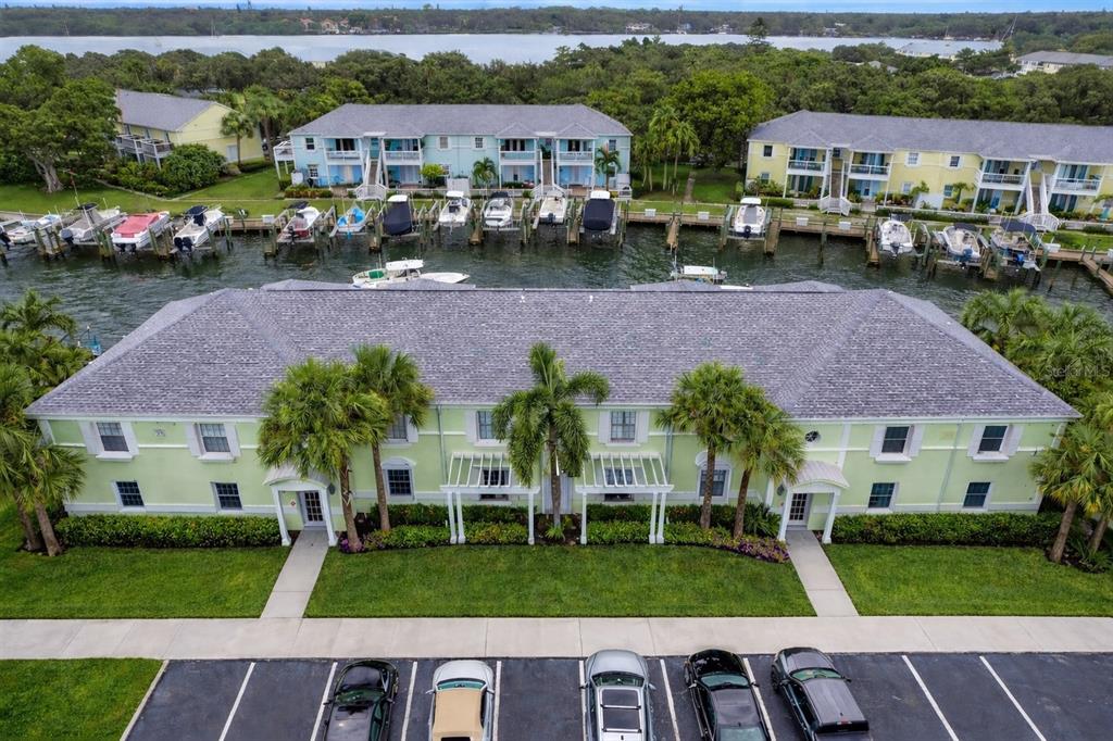 An aerial view shows a light green multi-story apartment building with a parking lot — 5245 COQUINA KEY DRIVE SE UNIT D, ST PETERSBURG, FL