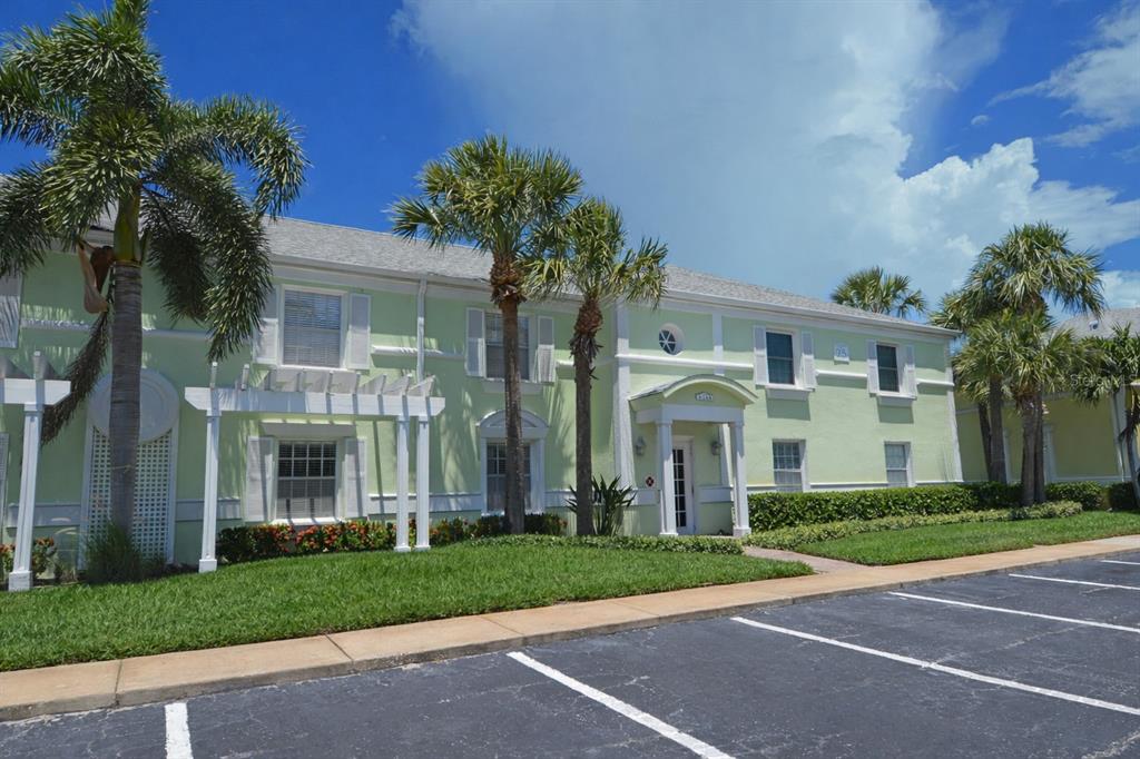 A two-story light green building with a white pergola and palm trees in front — 5245 COQUINA KEY DRIVE SE UNIT D, ST PETERSBURG, FL