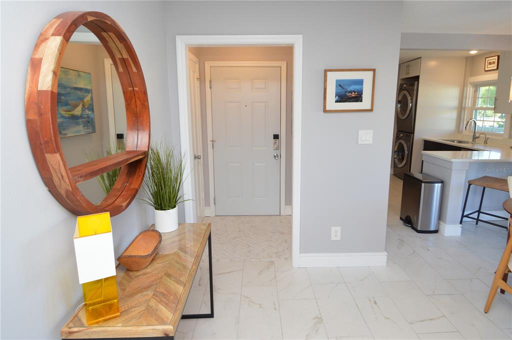 An entryway features a round wooden mirror, a console table, and white tile flooring — 5245 COQUINA KEY DRIVE SE UNIT D, ST PETERSBURG, FL