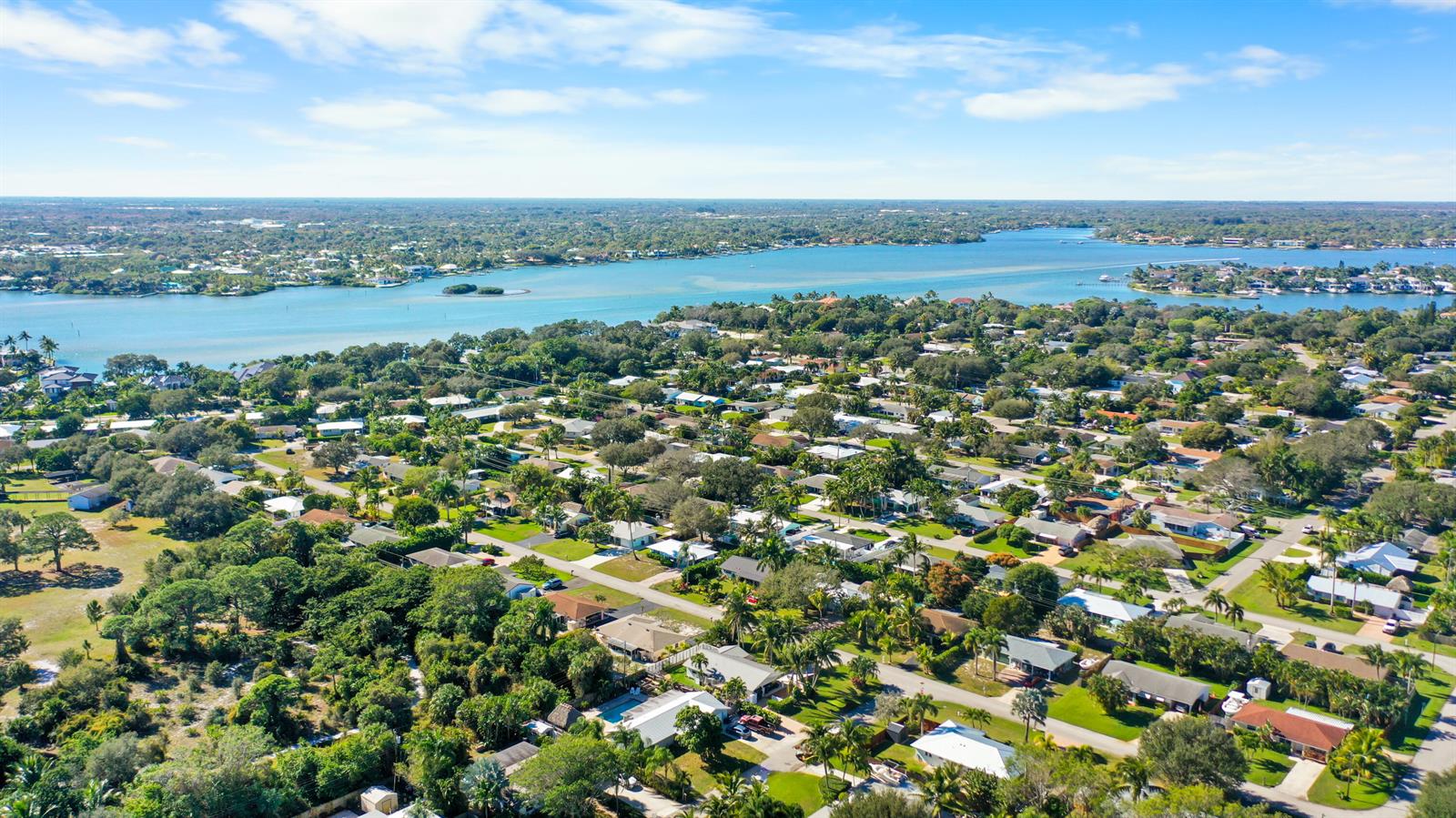 An aerial view shows a residential neighborhood situated along a wide, blue waterway — 1605 Treemont Avenue, Jupiter FL 33469, JUPITER, FL