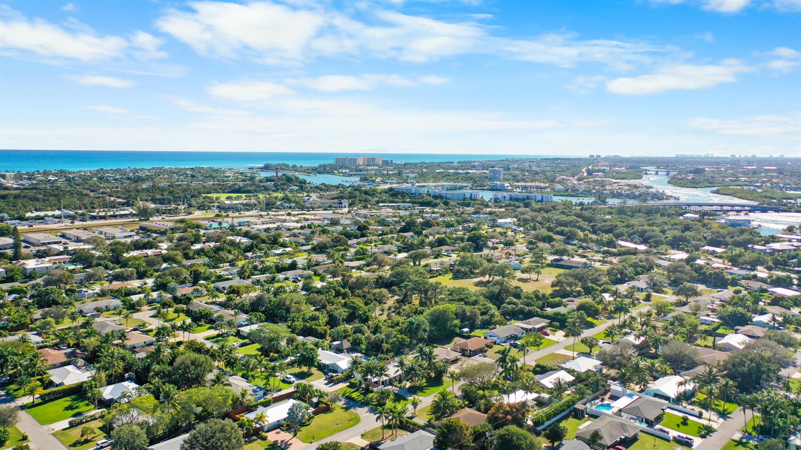 An aerial view shows a residential neighborhood with lush trees near a coastal waterway — 1605 Treemont Avenue, Jupiter FL 33469, JUPITER, FL