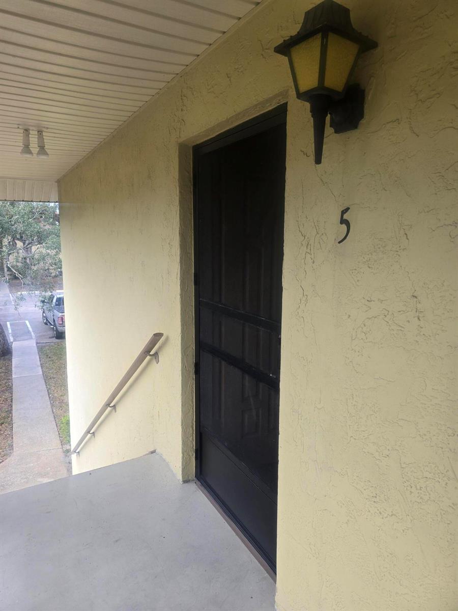 A tan exterior wall features a black screen door labeled with the number five — 400 18th Street # 5, Vero Beach FL 32960, VERO BEACH, FL