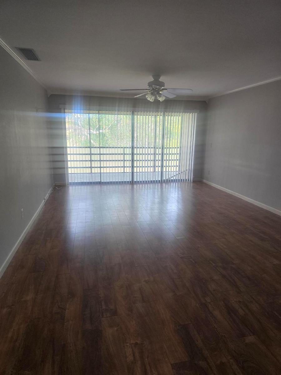 An empty living room features wood-look flooring, light gray walls, and a sliding glass door — 400 18th Street # 5, Vero Beach FL 32960, VERO BEACH, FL