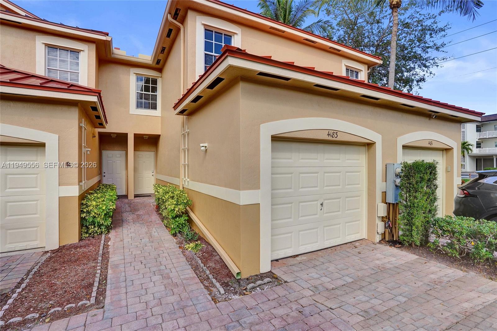 A two-story tan stucco townhouse with a brick walkway and two garage doors — 4183 Crystal Lake Dr, Deerfield Beach FL 33064, DEERFIELD BEACH, FL
