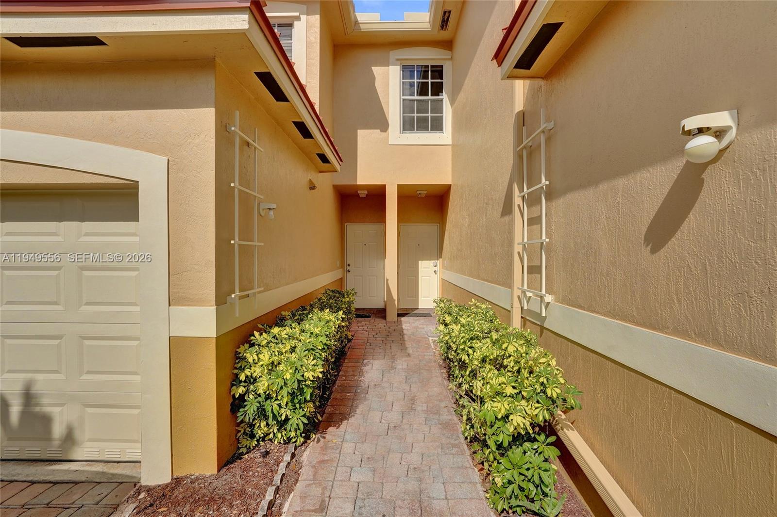 A paved walkway leads to two front doors between two beige stucco building walls — 4183 Crystal Lake Dr, Deerfield Beach FL 33064, DEERFIELD BEACH, FL