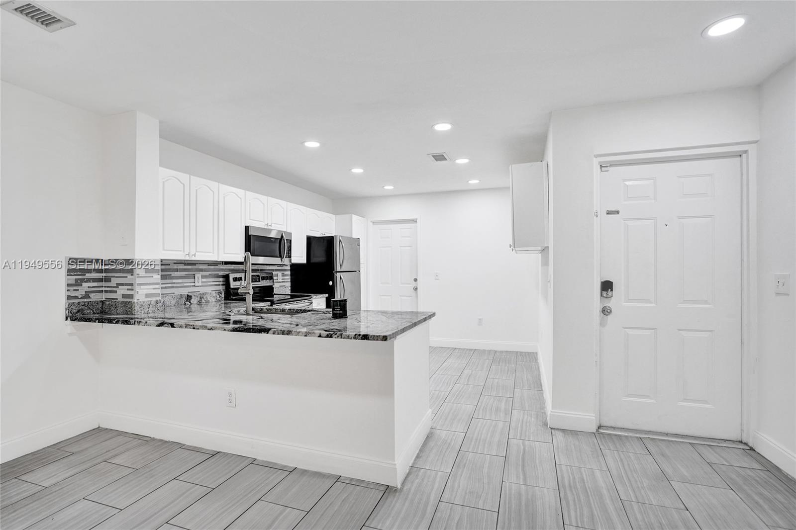 A kitchen with white cabinets, granite countertops, and tile flooring features an open floor plan — 4183 Crystal Lake Dr, Deerfield Beach FL 33064, DEERFIELD BEACH, FL