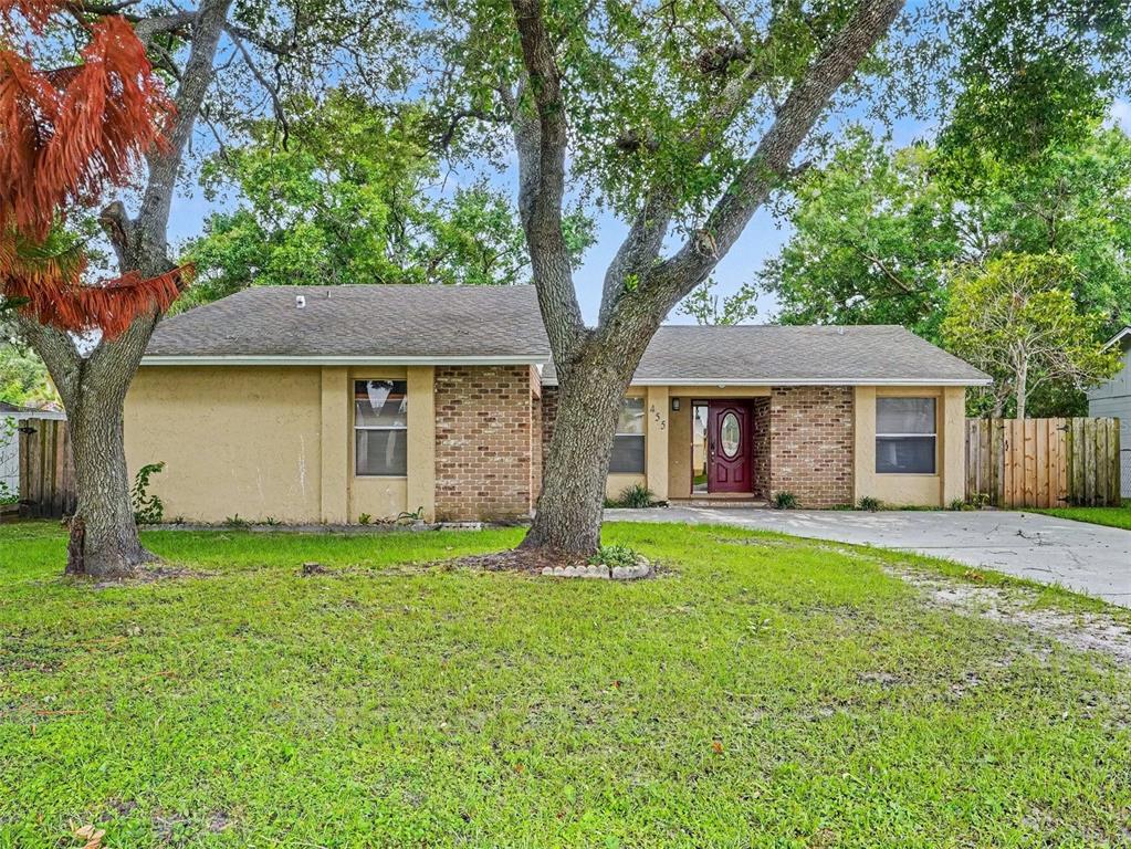 A single-story house with a brick and stucco facade, a red door, and large trees — 455 CART COURT, KISSIMMEE, FL