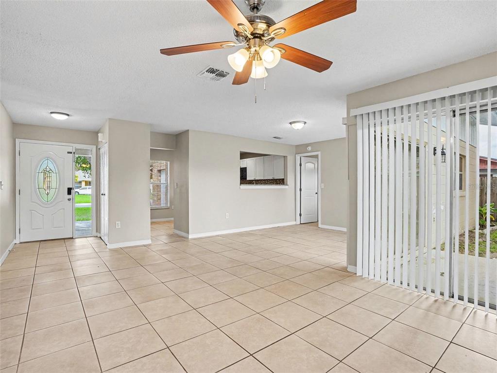 A living area with tile floors, a ceiling fan, and a sliding glass door — 455 CART COURT, KISSIMMEE, FL