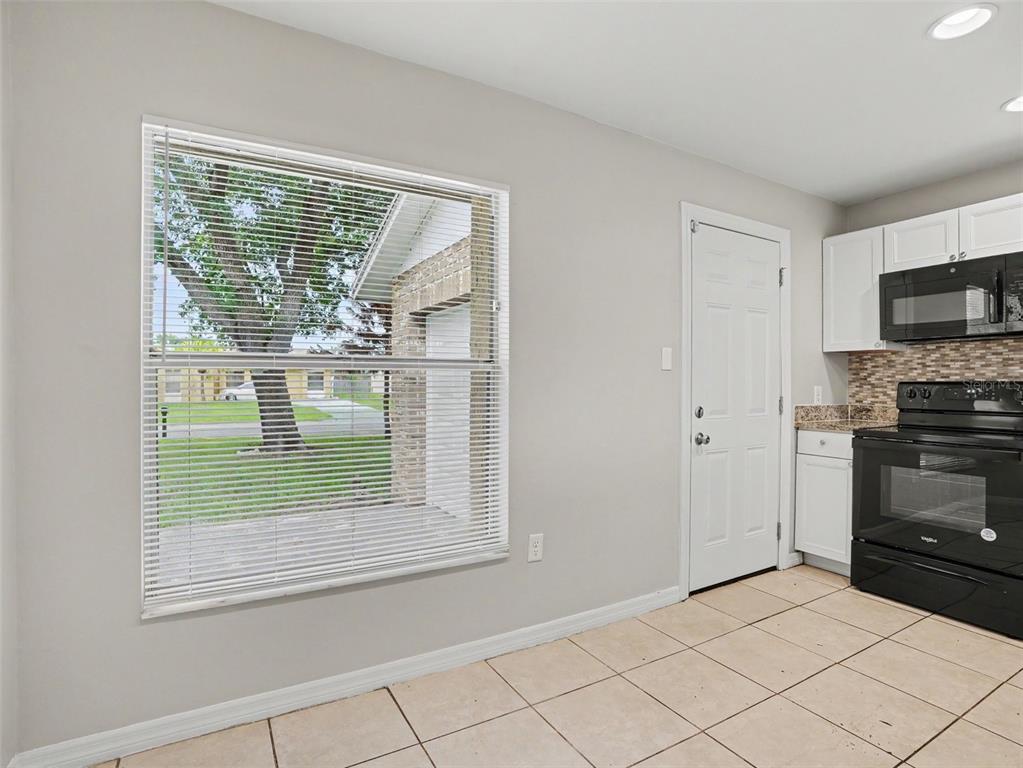 A kitchen with white cabinets, black appliances, tile flooring, and a large window — 455 CART COURT, KISSIMMEE, FL