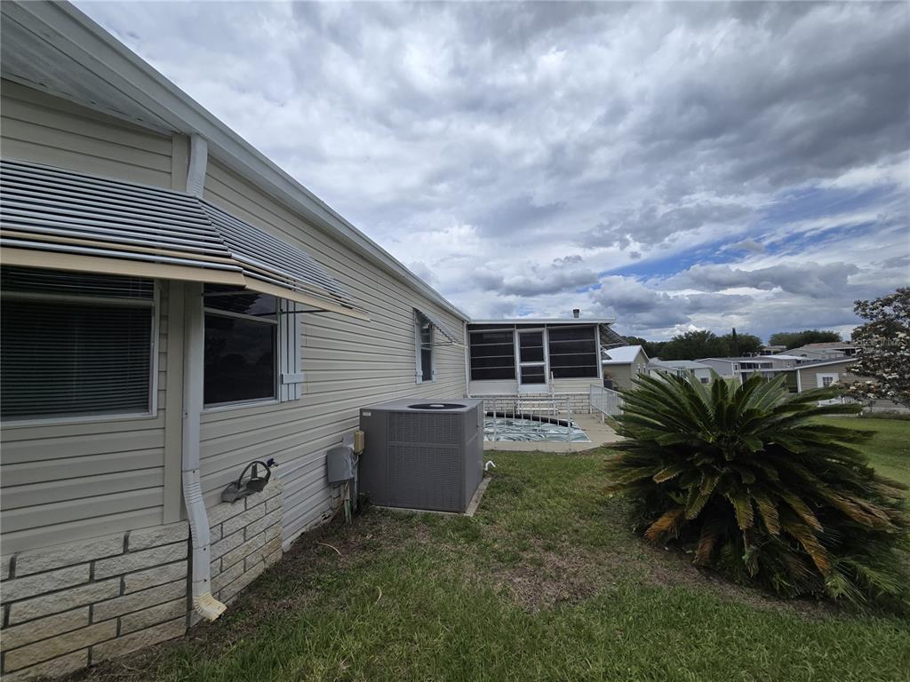 The exterior of a house features beige siding, a central air conditioning unit, and a patio — 4122 GREENBLUFF ROAD UNIT 821, ZELLWOOD, FL