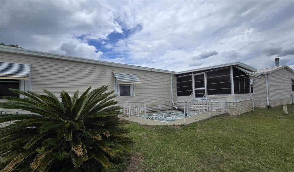 A side view of a mobile home with a screened-in porch and a concrete patio — 4122 GREENBLUFF ROAD UNIT 821, ZELLWOOD, FL