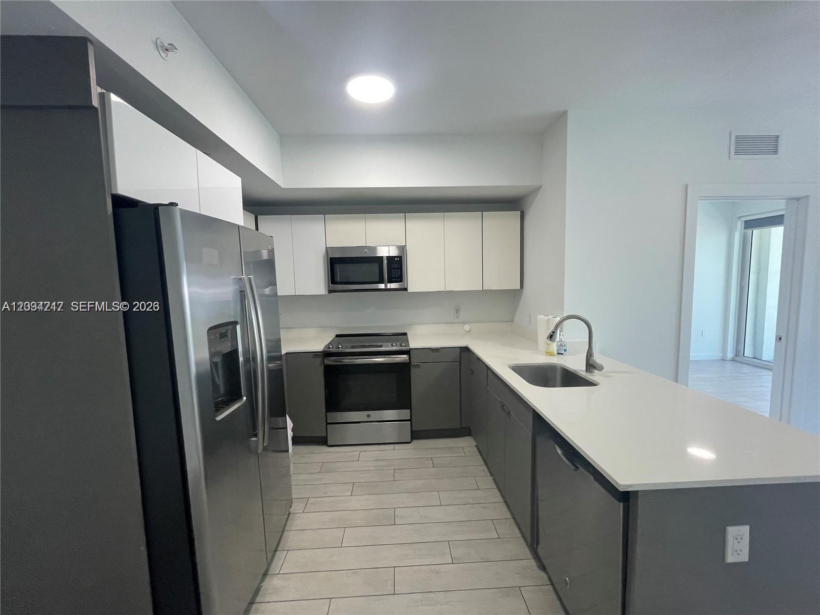 A modern kitchen features stainless steel appliances, white upper cabinets, gray lower cabinets, and countertops — 321 NE 26th St # 512, Miami FL 33137, MIAMI, FL