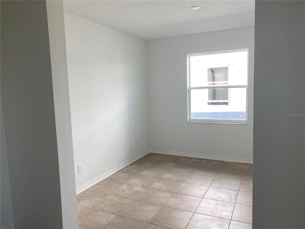 A small, empty room features white walls, tile flooring, and a single window — 10725 NEW MORNING DRIVE, TAMPA, FL