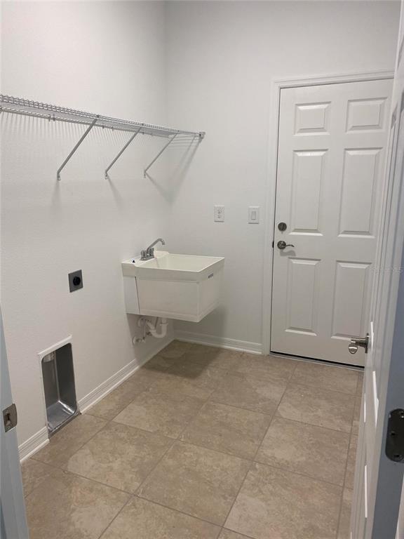 A laundry room features a utility sink, wire shelving, and a white door — 10725 NEW MORNING DRIVE, TAMPA, FL