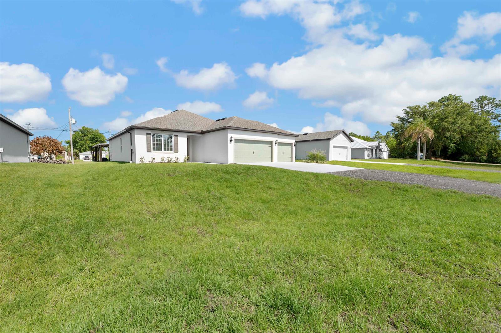 A single-story house with a light-colored exterior and a two-car garage sits on a lawn — 8225 95th Avenue, Vero Beach FL 32967, VERO BEACH, FL