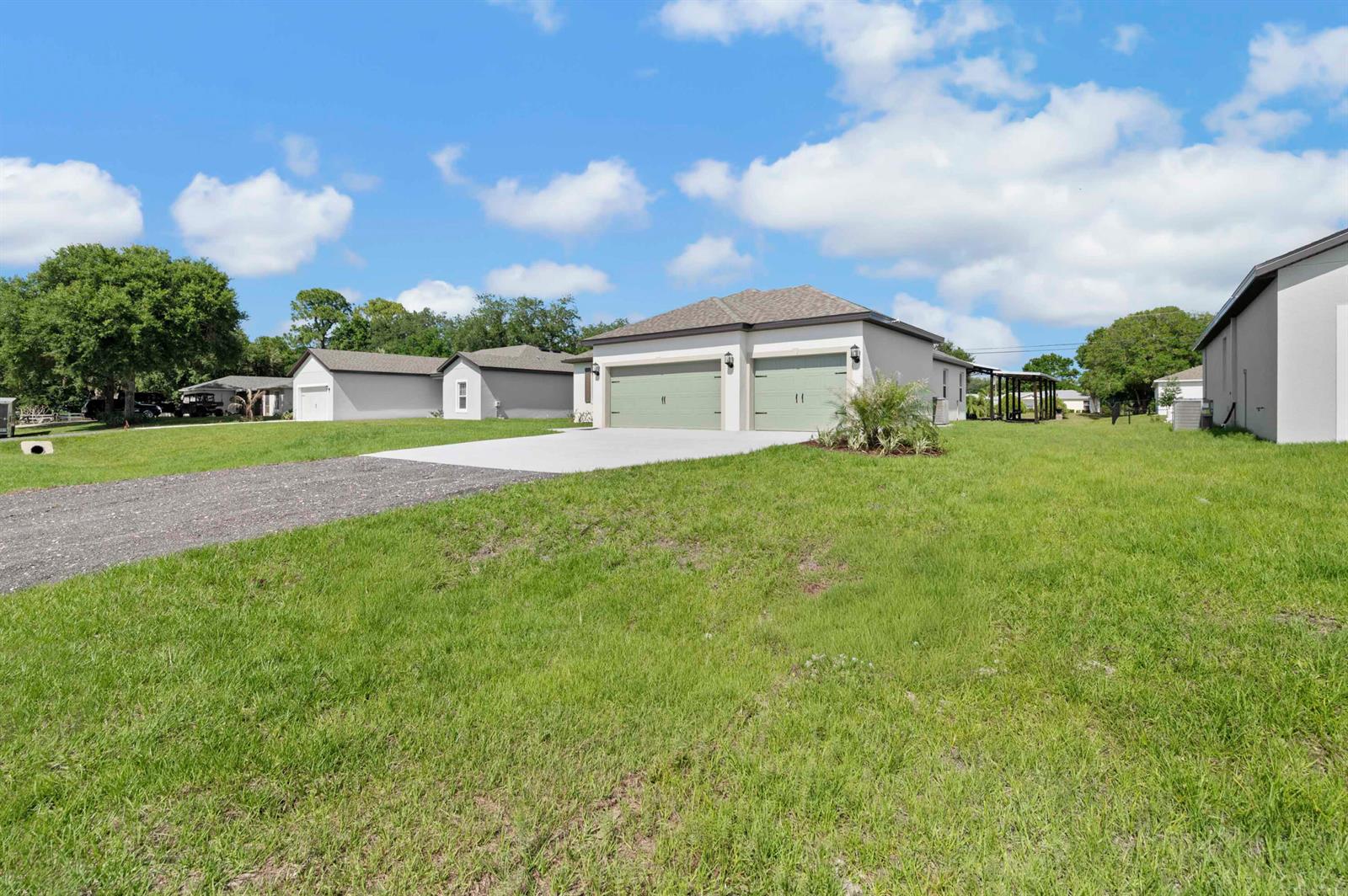 A single-story house with a two-car garage and a concrete driveway sits on a grassy lot — 8225 95th Avenue, Vero Beach FL 32967, VERO BEACH, FL