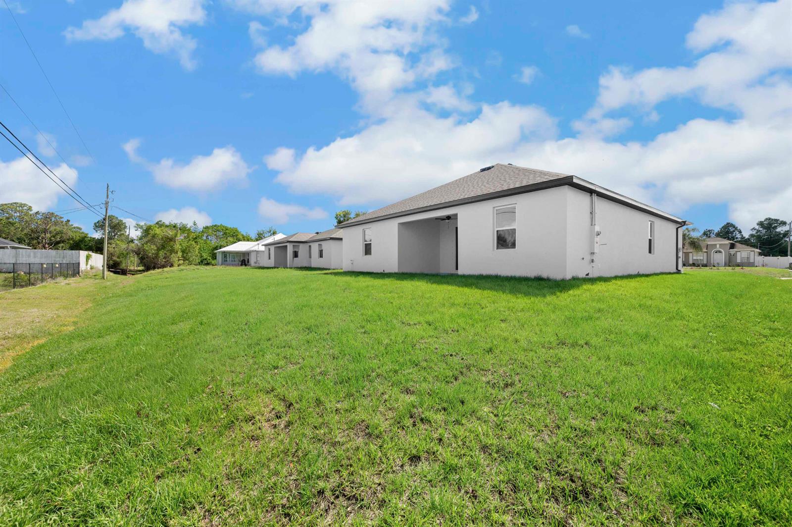 A white single-story house with a covered patio sits on a large, grassy lot — 8225 95th Avenue, Vero Beach FL 32967, VERO BEACH, FL
