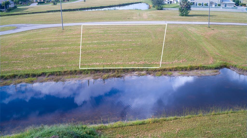 An aerial view shows a vacant, rectangular residential lot situated between a road and water — 24060 CHERRYSTONE LANE, PUNTA GORDA, FL