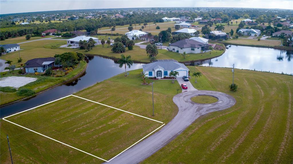An aerial view shows a vacant rectangular residential lot outlined in white near a cul-de-sac — 24060 CHERRYSTONE LANE, PUNTA GORDA, FL