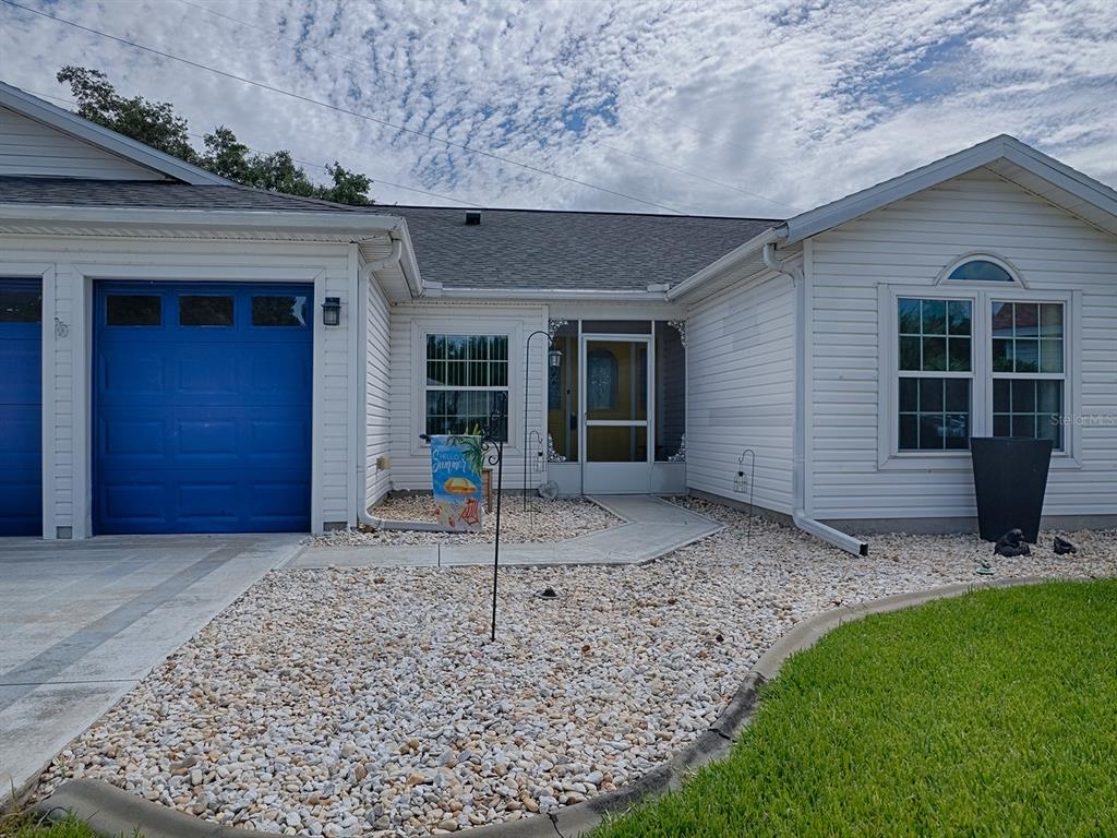 A white house with a blue garage door and a gravel front yard — 3851 MANOR OAKS COURT, LEESBURG, FL
