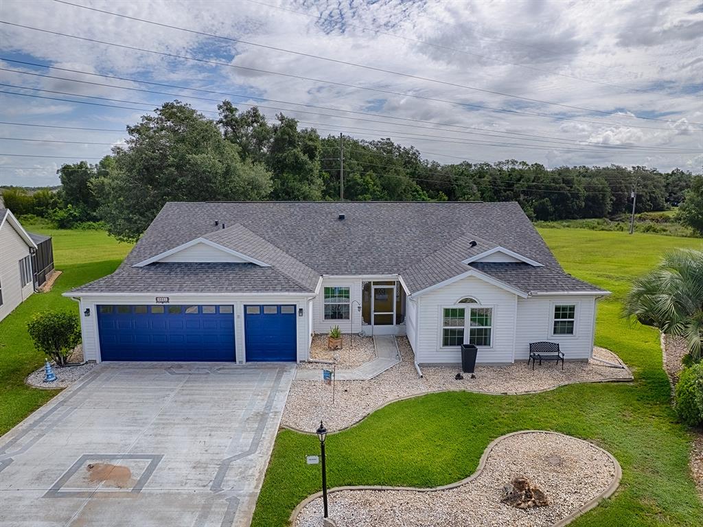 An aerial view of a single-story white house with a blue garage and gravel landscaping — 3851 MANOR OAKS COURT, LEESBURG, FL