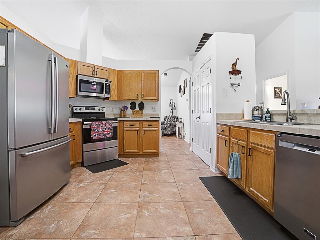 A kitchen with stainless steel appliances, oak cabinets, and tile flooring — 3851 MANOR OAKS COURT, LEESBURG, FL