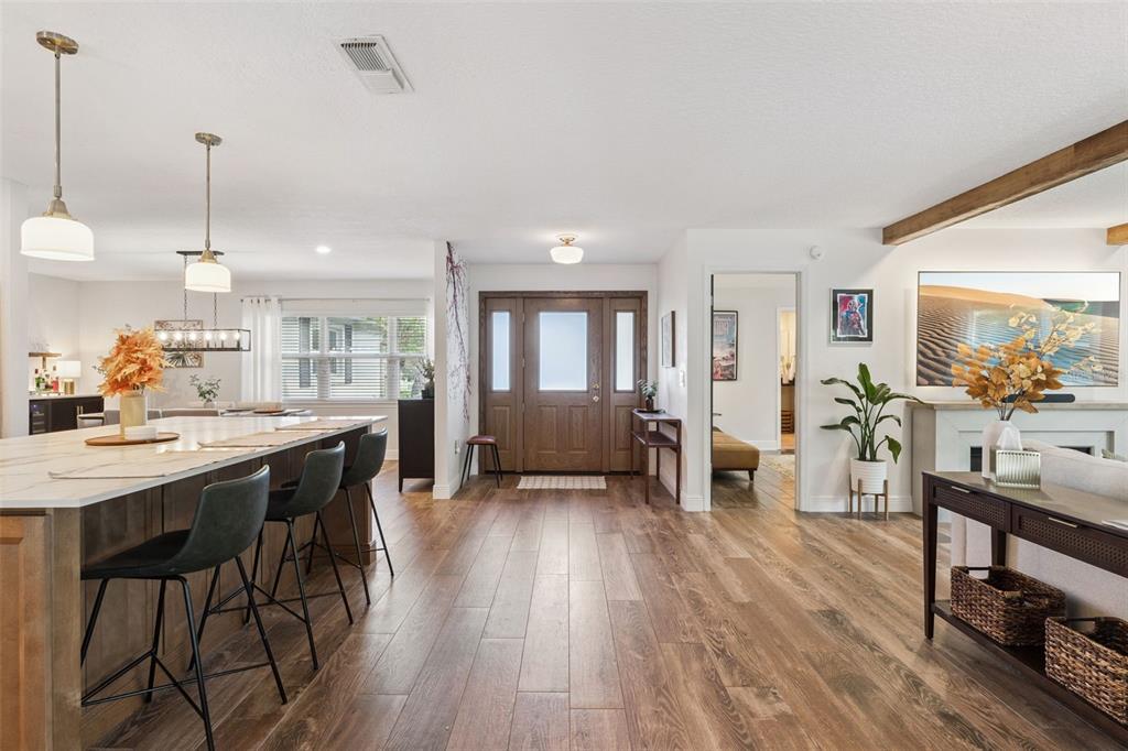 A bright, open-concept living area features a kitchen island, wood flooring, and a front entryway — 8156 CARAWAY DRIVE, ORLANDO, FL