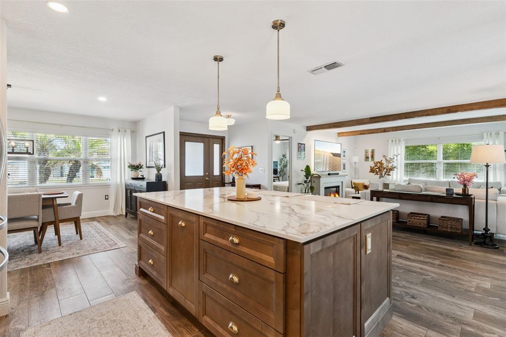 A kitchen island with a marble countertop sits in an open-concept room with wood floors — 8156 CARAWAY DRIVE, ORLANDO, FL