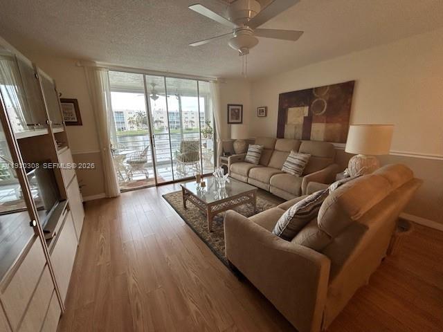 A living room features light wood flooring, a beige sofa, and a sliding glass door — 324 SE 10th St # 207, Dania Beach FL 33004, DANIA BEACH, FL