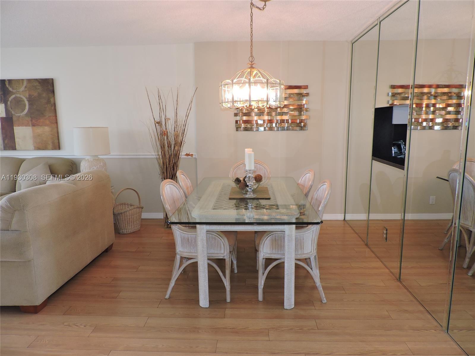 A dining area features a glass-topped table, wicker chairs, and a mirrored wall — 324 SE 10th St # 207, Dania Beach FL 33004, DANIA BEACH, FL